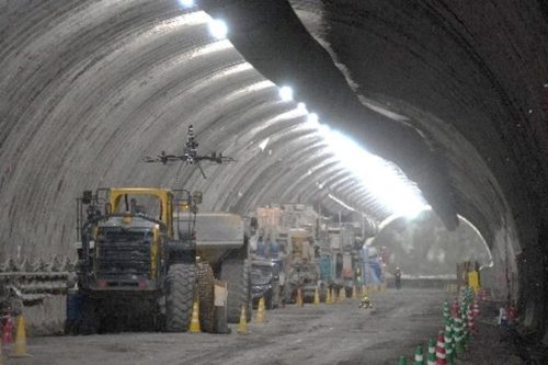 トンネル坑内の重機や機材をかすめて飛行するドローン（以下の写真、資料：センシンロボティクス）