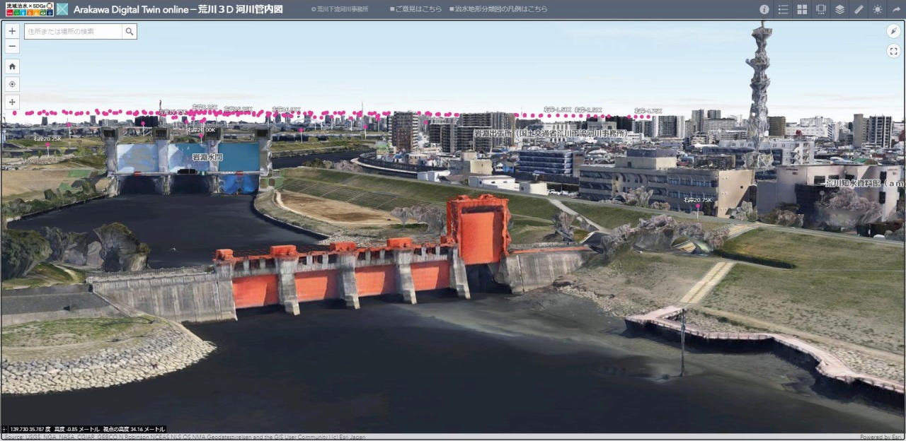 3D管内図で荒川下流河川事務所や旧岩淵水門（赤色）、岩淵水門（青色）を見たところ。背景の街並みは、PLATEAUのテクスチャー付き（LOD2）データを利用し、リアルになっている
