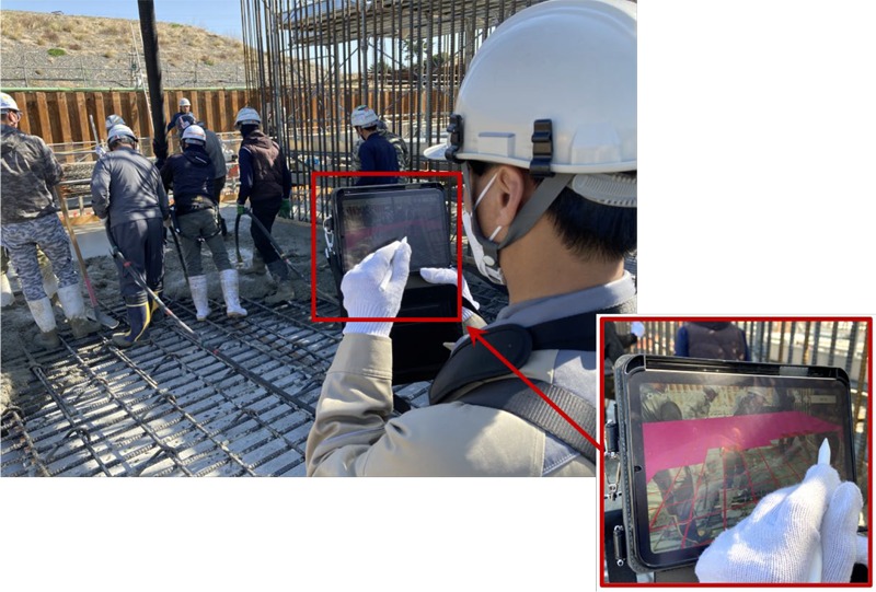 「ARコンクリート締固め管理システム」を使った施工管理。iPadの画面上（右下）には、まだ締固めされていない部分が赤く表示されているのがわかる（以下の写真、資料：三井住友建設）