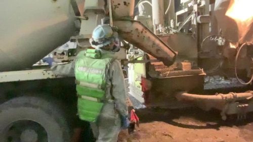 トンネル現場でコンクリートポンプ車のレバー操作を行う作業員。防じんマスクを着け、粉じんや排ガスにさらされての過酷な作業だ（以下の写真、資料：アクティオ）