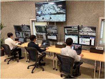 成瀬ダムの建機を鹿島西湘実験フィールドの遠隔管制室で制御するITパイロットたち