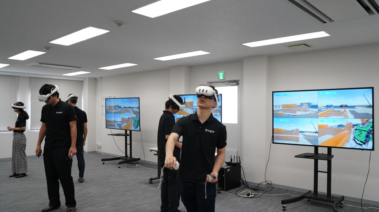 VRゴーグルを着け、「型枠メタバーストレーニング」で学ぶ受講者たち。大型ディスプレーには受講者たちの視点からの画像が映し出される(以下の写真、資料:積木製作)