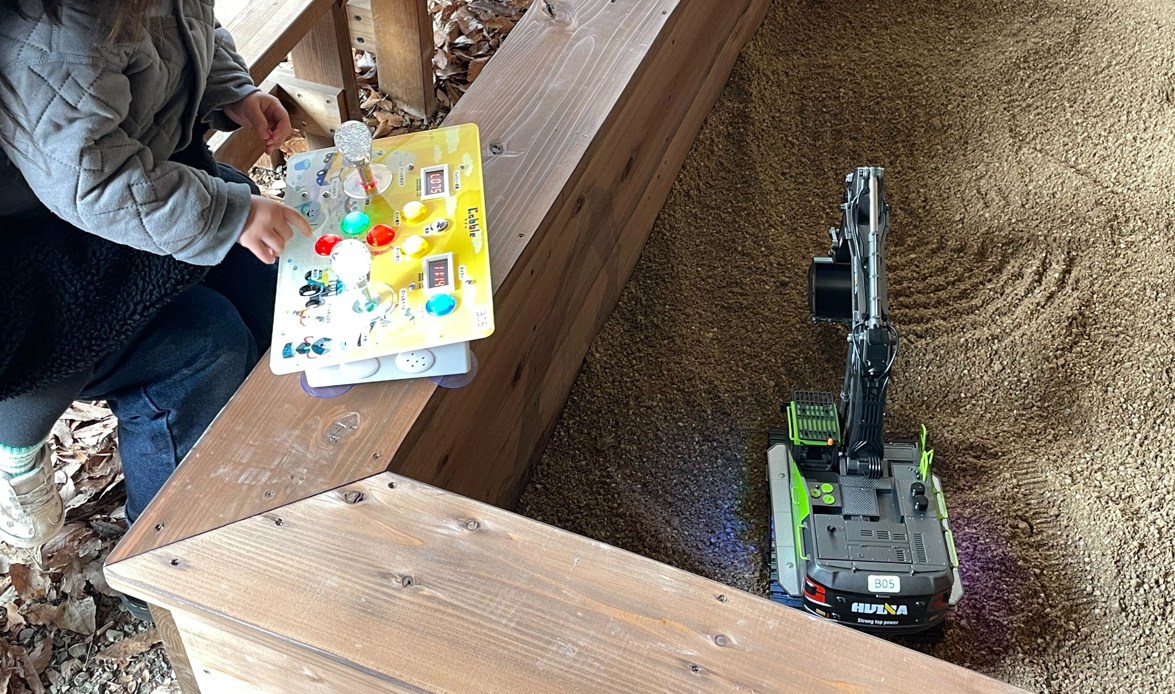 砂の中のお宝をショベルカーの遠隔操作で探すところ